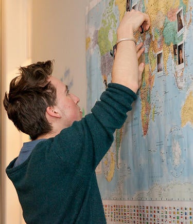 Student pins photos of people to a map of the world