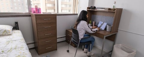 A student sitting in her residence room on her laptop.
