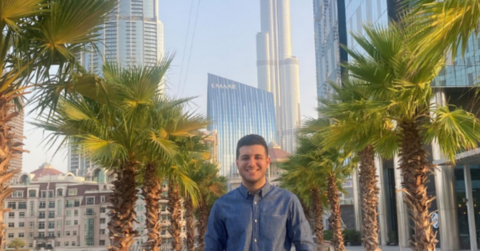 Souhail standing infront of palm trees and building in Dubai