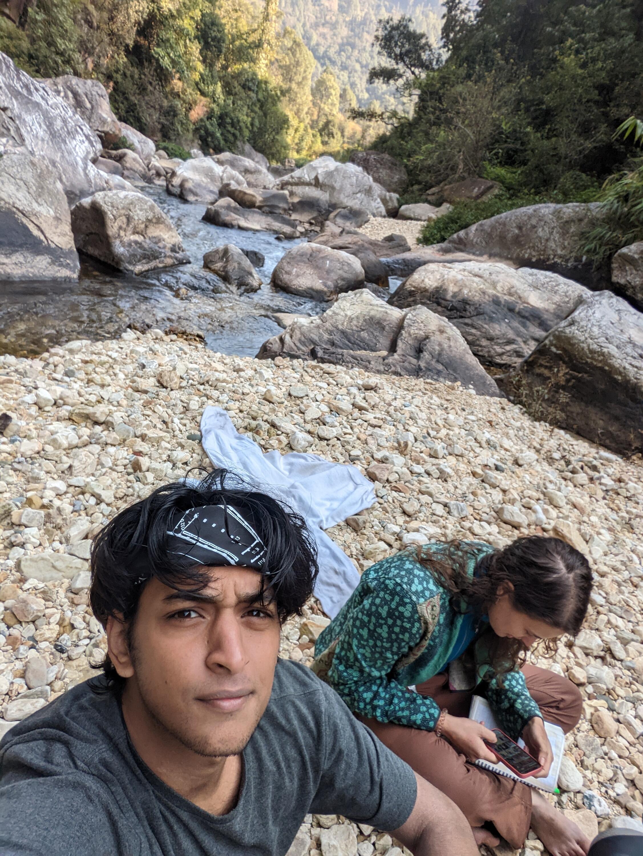 Aryaman and a friend sitting by the river.