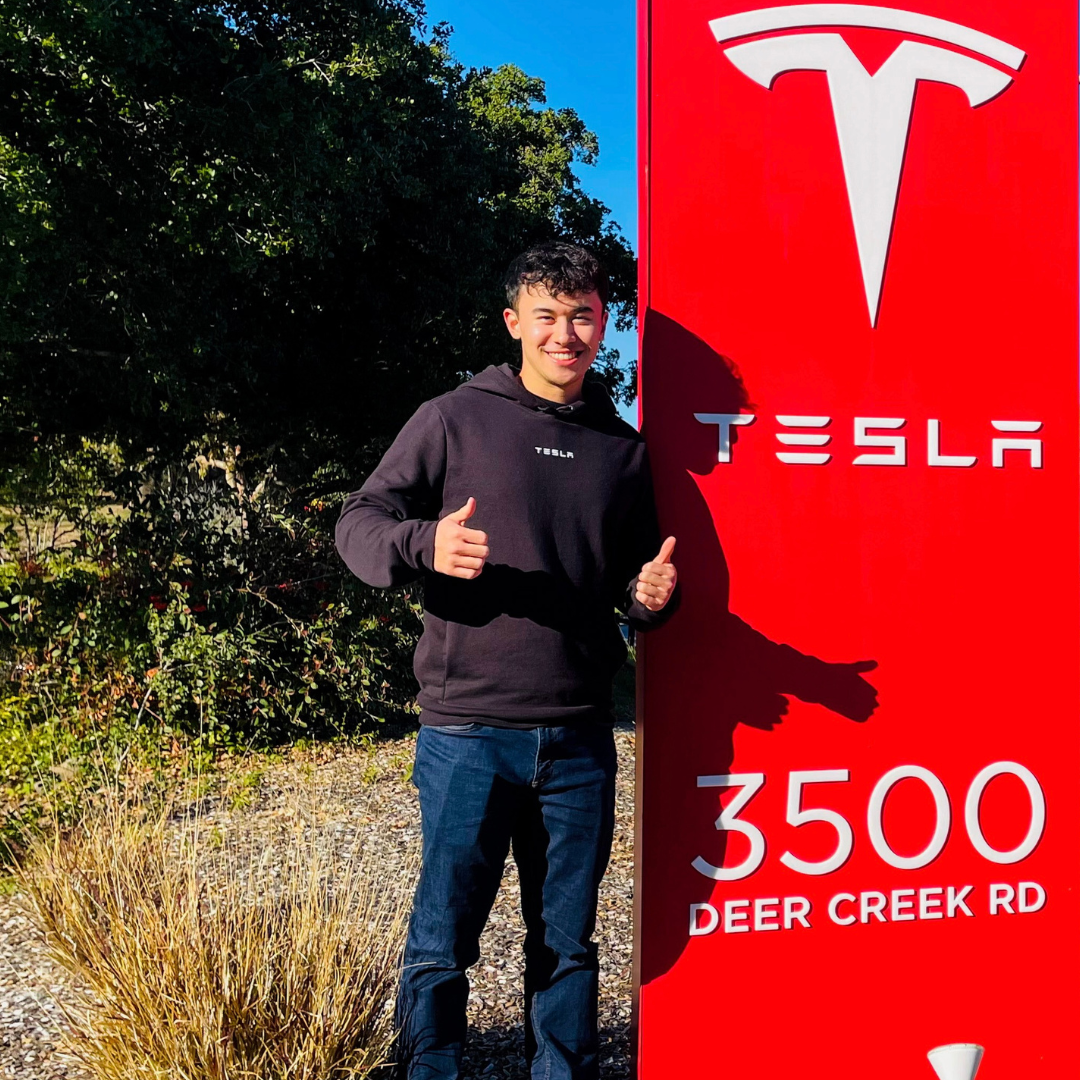 Brandon Goh, a co-op student standing in front of Tesla banner