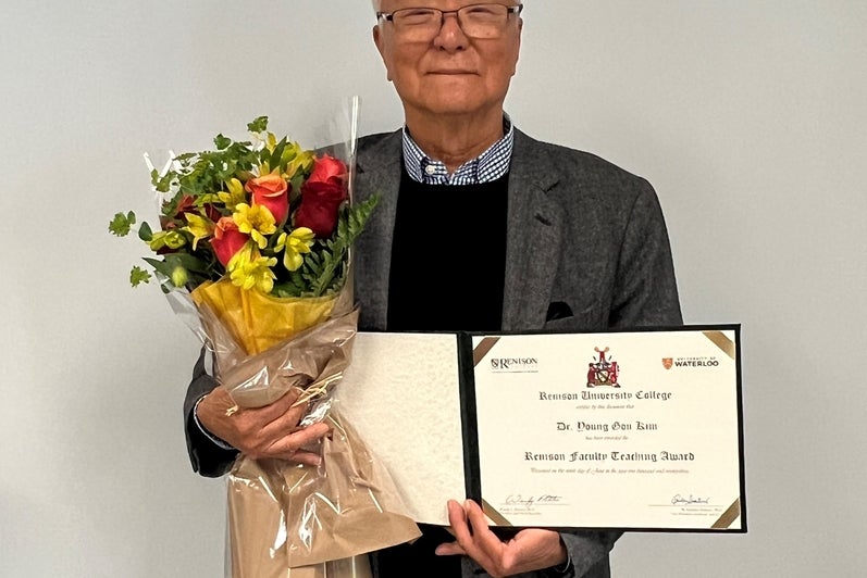 Dr. Kim standing holding his award