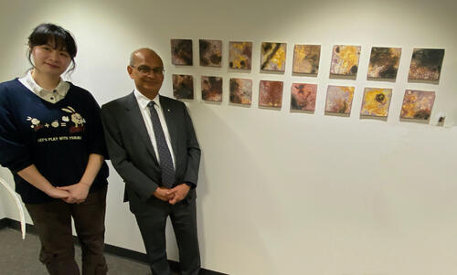 Mei and President Vivek Goel stand next to the Silent Explosion tiles installation.