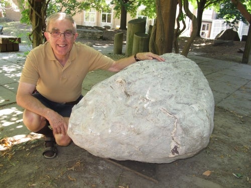 Boulder with man crouched beside it outdoors in the rock garden