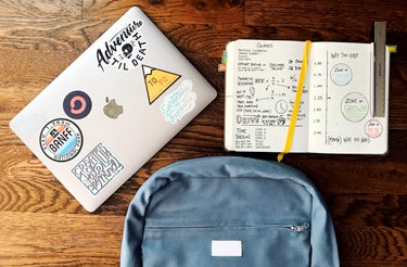 a laptop and daily planner on top of a wooden desk