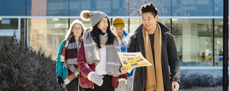 Group of students walking and looking at the campus map.