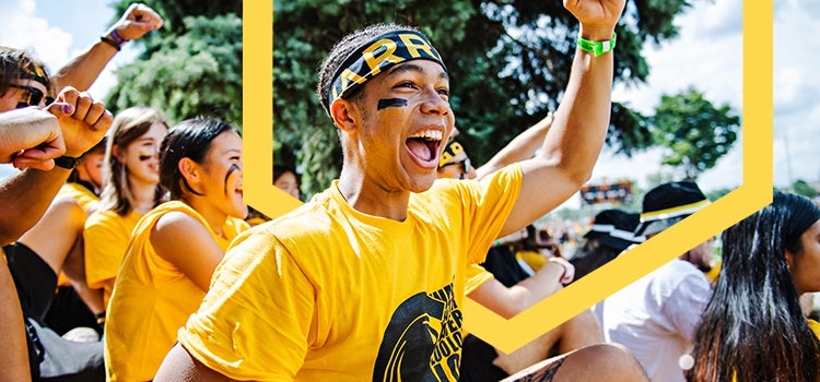 Waterloo student wearng bright gold Warriors t-short cheering at outdoor event.
