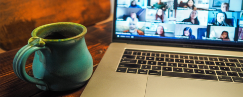 a coffee cup in front of a laptop with a virtual meeting taking place