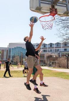 two students playing basketball on outdoor court