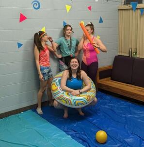 Four Grebel students dressed in swim gear standing on blue tarp