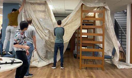 Students building an indoor fort with a tarp