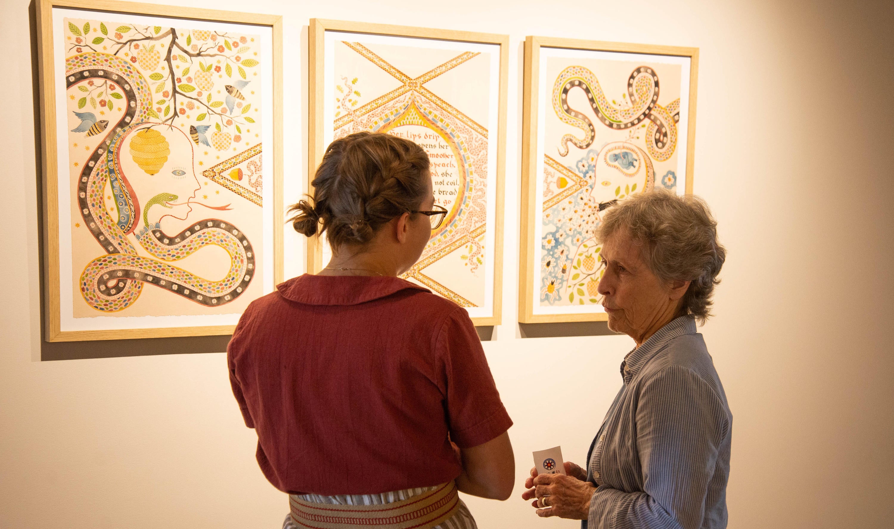 Meg Harder speaking with event attendee about her artwork.
