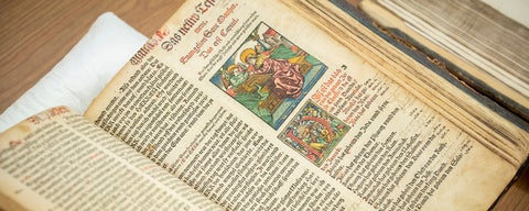 An overhead view of an open book from the archives. It's old, and has a colourful block print on the page