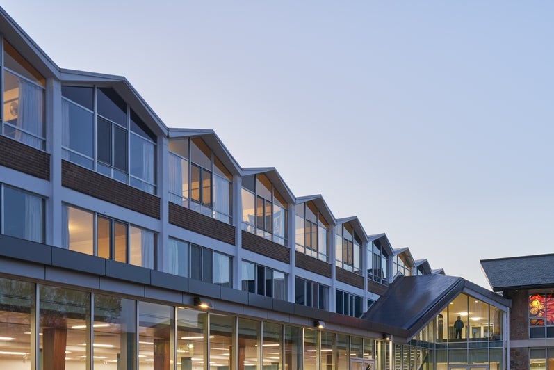 A view of the Grebel residence building at dusk, featuring its iconic peaked rooves.