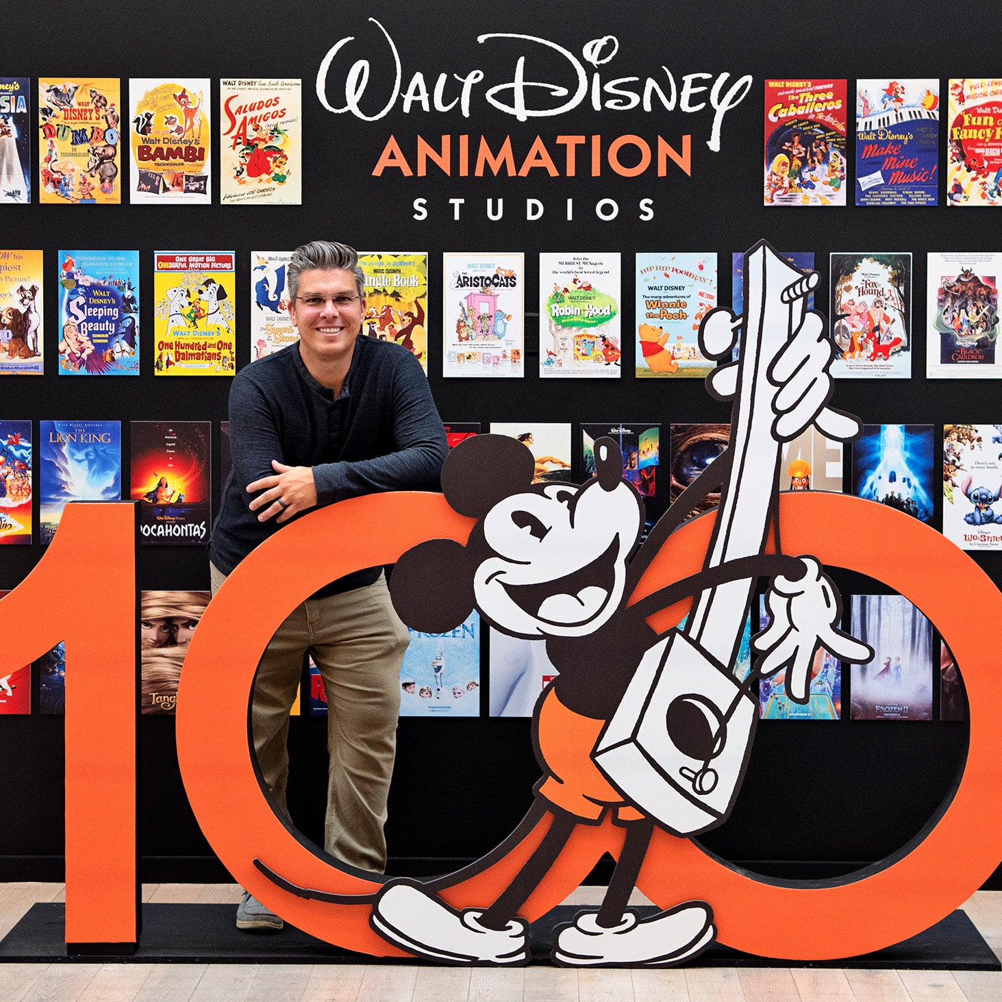 Greg Culp leaning against Mickey Mouse sign in Disney Animation Studios