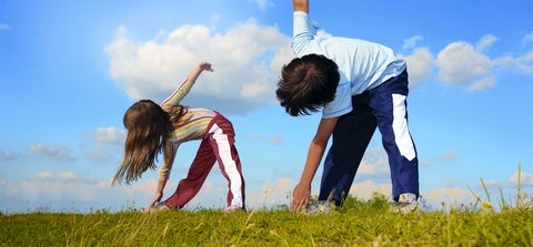 Two young children exercising on a hill on a sunny day.