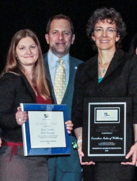 Margo Hilbrecht holding framed award