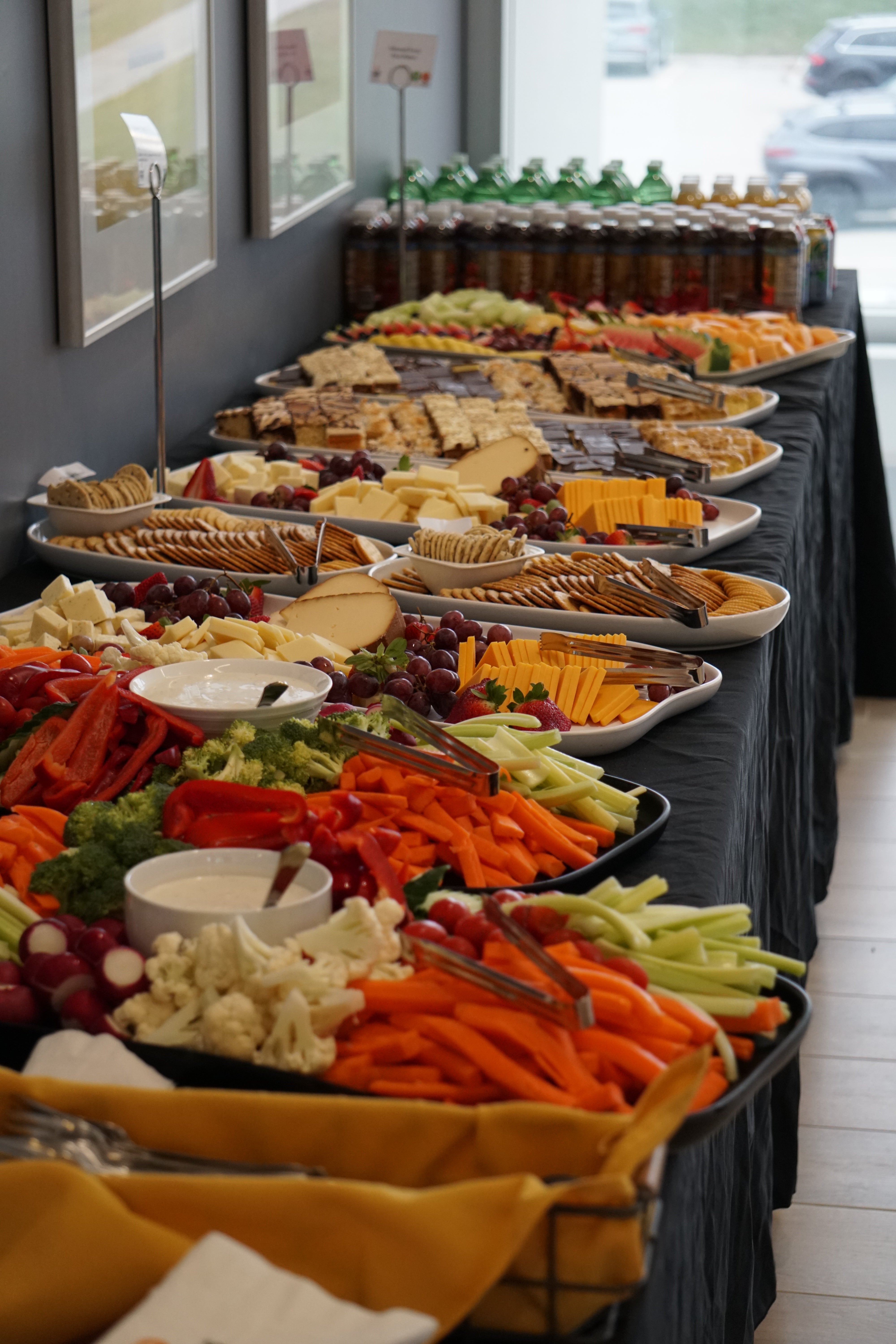 Spread of food including veggies, dips, cheeses, fruit and desserts.