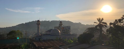 Sunrise over city in Uganda with mountain in the background