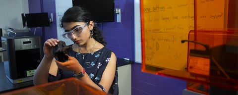 Student looking at 3D printed object in lab