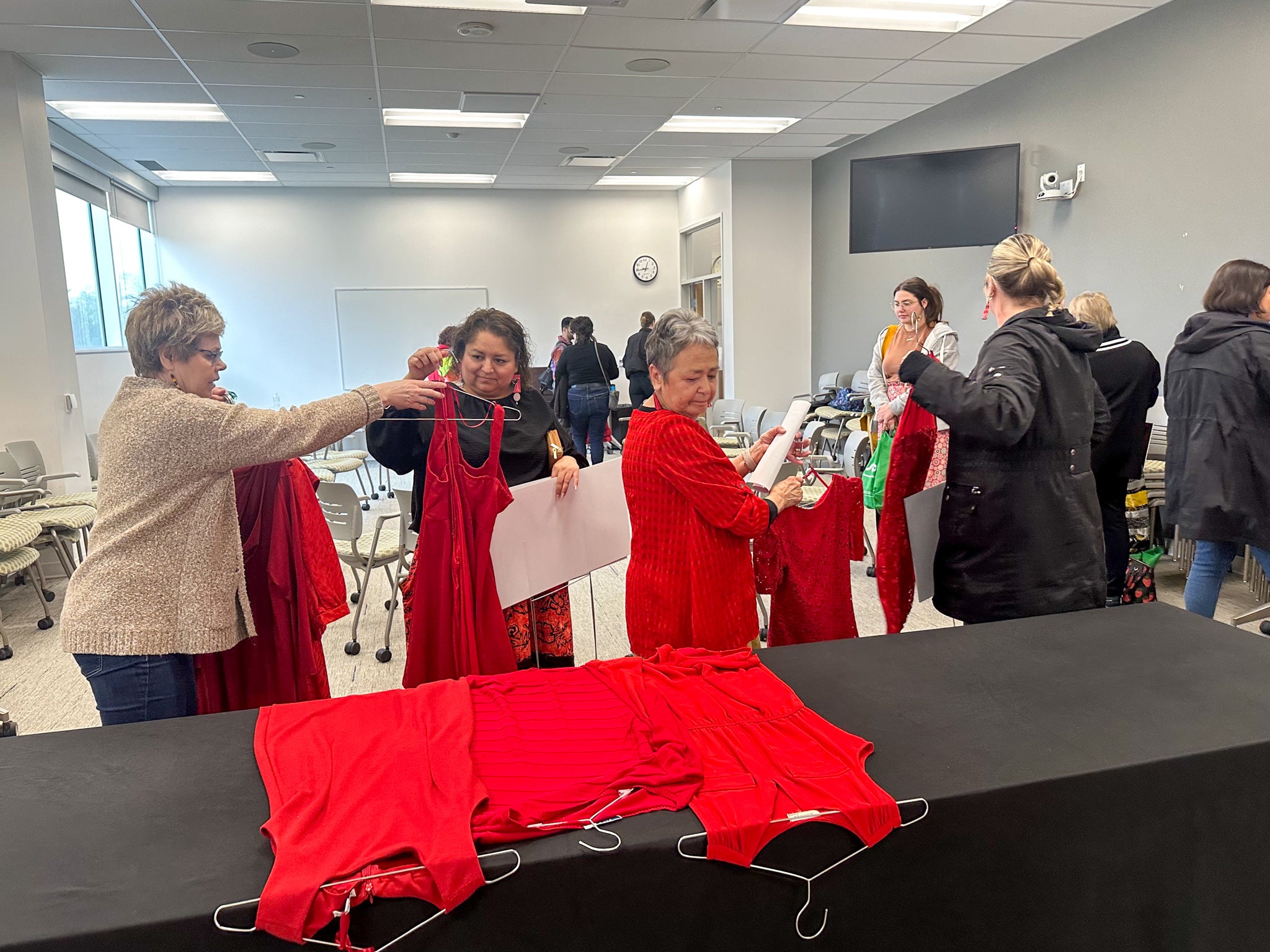 Jean Becker and Robin Jones-Stadelbauer gather red dresses onto a table for the Red Dress Day commemoration ceremony 