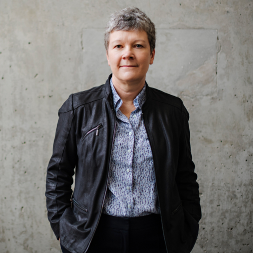 Nancy Vanden Bosch wearing standing against a concrete wall in a leather jacket