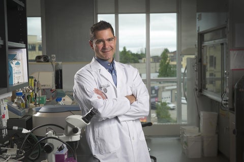 Roderick Slavcev in a lab coat standing in lab