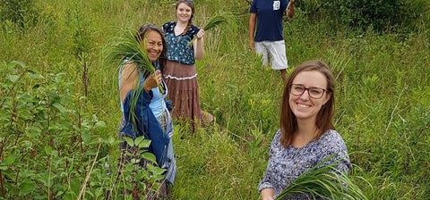 Students on medicine walk standing in a field of grass and smiling