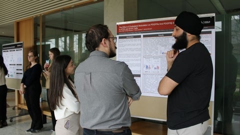 A group pf people standing around a research poster