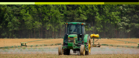A wide shot of a Green Tractor watering a field. 
