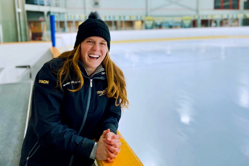 Haley Baxter laughing and standing at the side of a hockey rink.