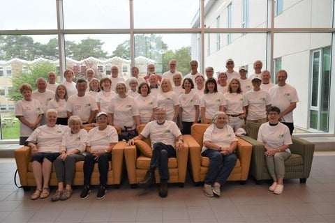 Group of alumni gathered in the Renison Atrium for a group photo. Each is wearing a matching t-shirt in celebration of the reunion weekend. 