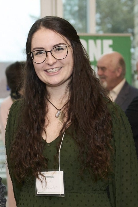 Rachael Fowler at a recent event. She is wearing a green dress and glasses, and is smiling at the camera.