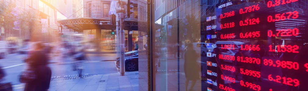 Digital image of currency exchange rates in a store front window with people walking by on the sidewalk