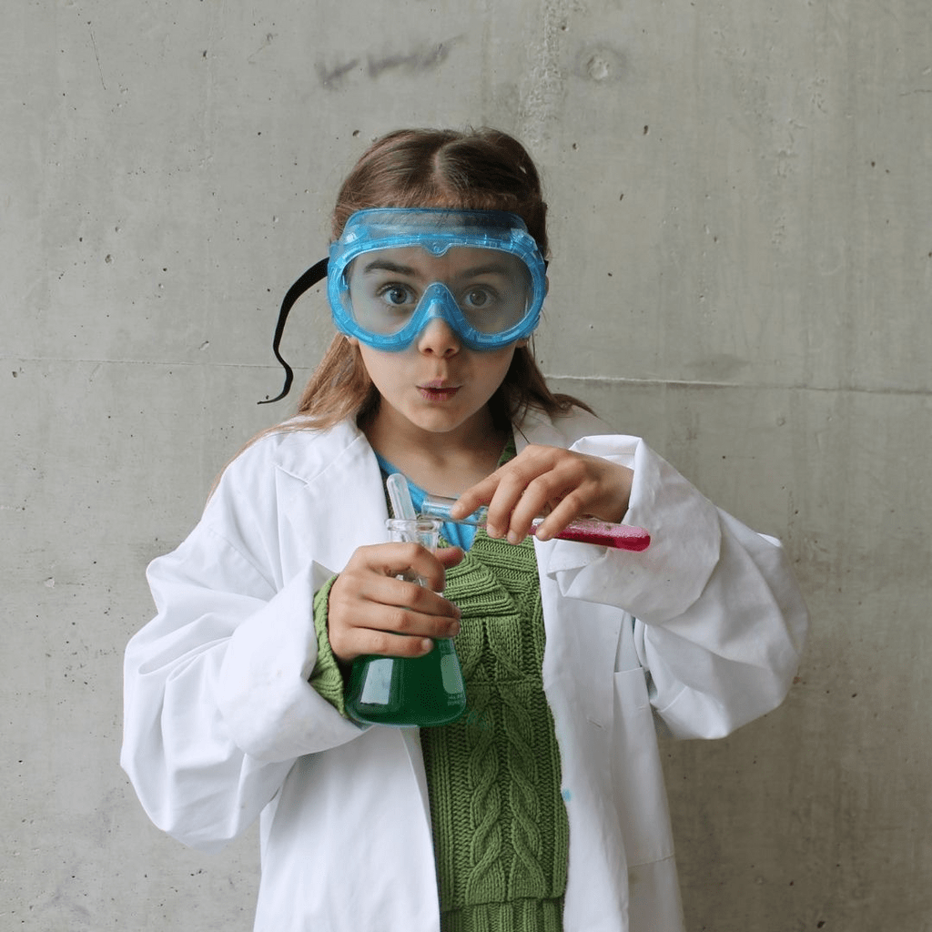 Young child dressed as scientist holding a beaker.