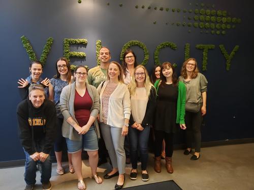 A group of St. Paul's staff stand in front of the Velocity sign
