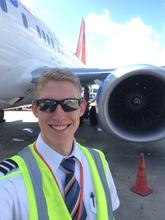 Spencer in his pilot's uniform standing beside a Sunwing Airlines 737