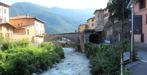 Buildings connected by a bridge over looking mountains and a stream below