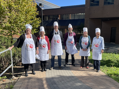 The Faculty deans wearing chefs hat and aprons that say &quot;United Way&quot;