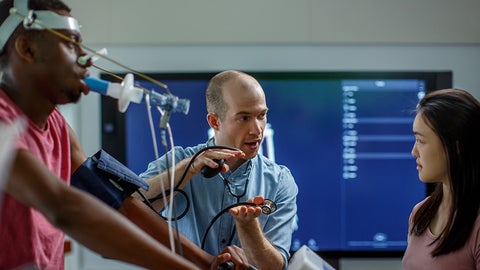 Instructor explaining a process to a student with a subject on a VO2 max machine