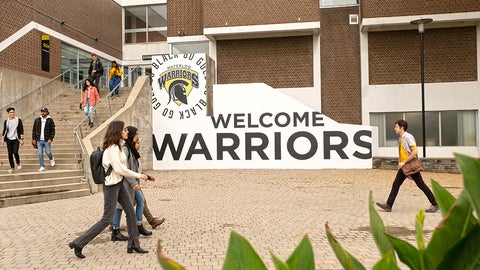 Students walking across Waterloo's Welcome Warriors sign