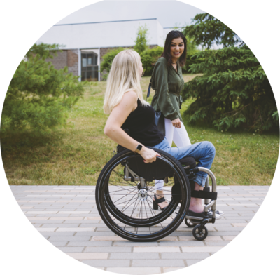 A woman walking alongside a woman on a wheelchair