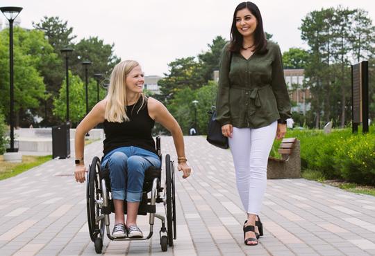 two women moving towards the you one is in a wheel chair