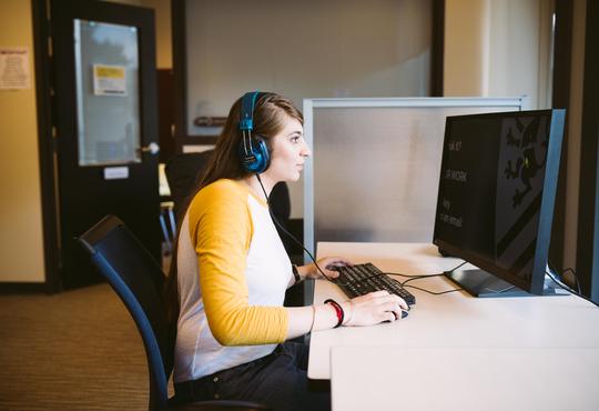 A woman with headphones on working on the computer