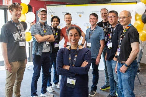 A smiling woman standing among a group of men