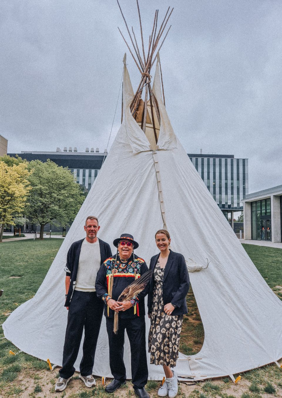 Two Saxion students standing with Elder Henry in front of Tipi