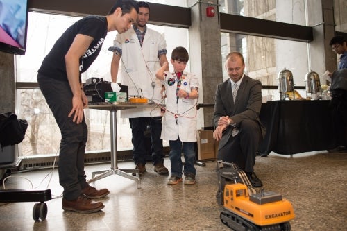 A visitor to the Science Centre tries controlling a model excavator using only his arm muscles, while researcher Michael Barnett-Cowan (right) looks on.
