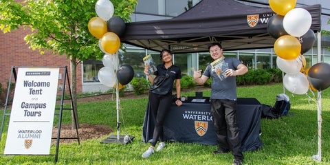 Volunteers standing and smiling at a welcome tent