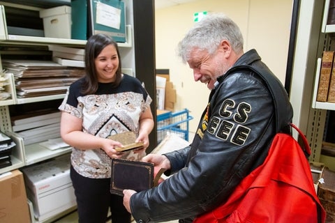 Alum in a leather jacket talking to a staff member in the Library