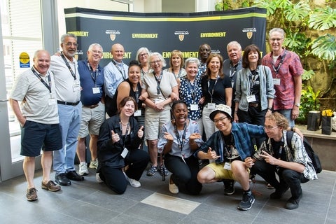 Group of Environment alumni in front of a backdrop